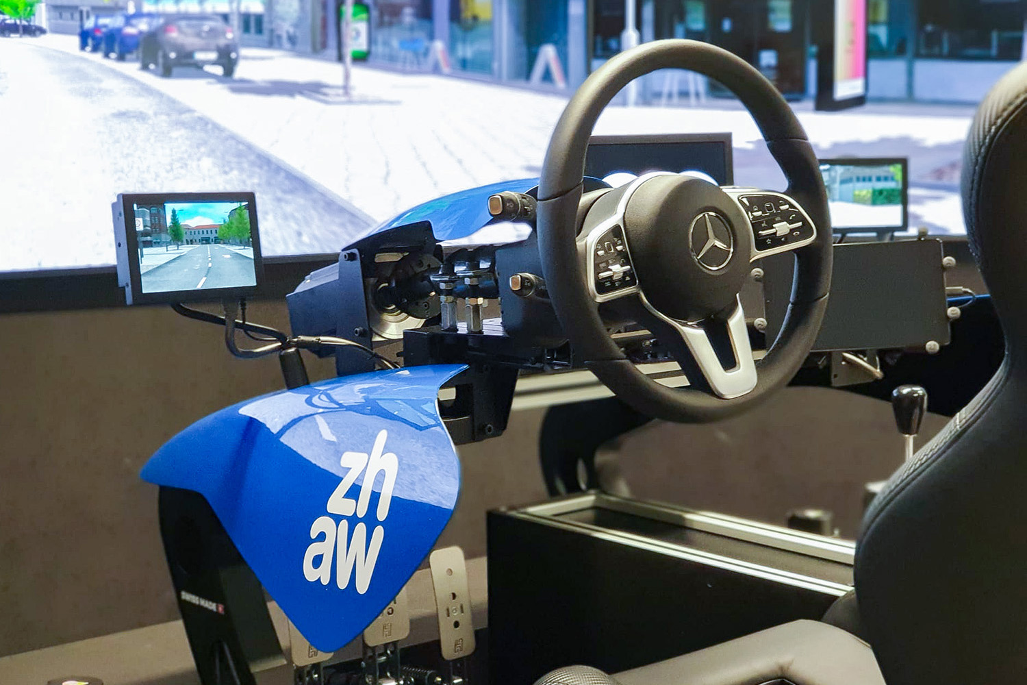 Simulateur de véhicule avec volant Mercedes, garnitures bleues et vue sur la rue sur un écran.