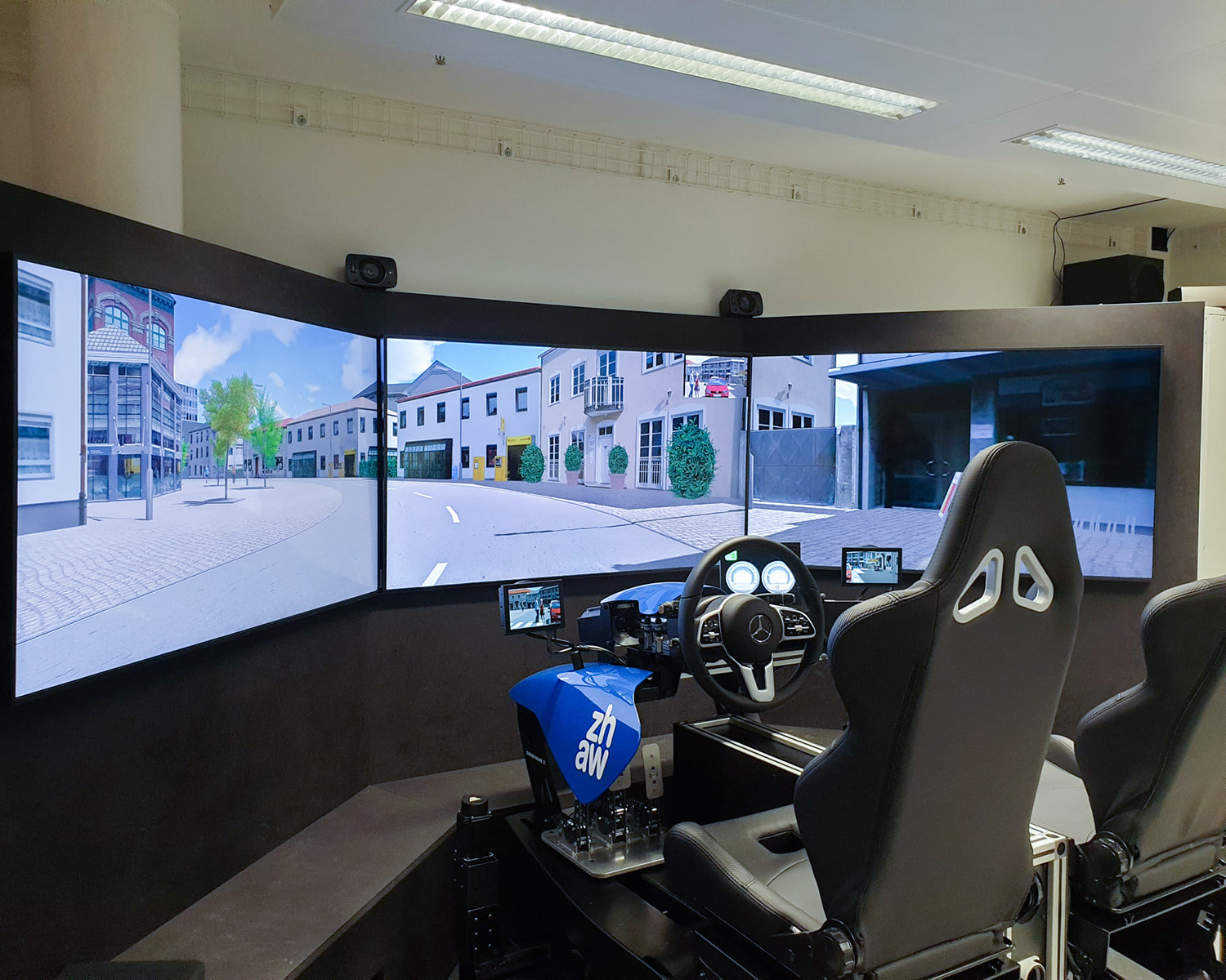 Le simulateur de conduite avec trois moniteurs montre une vue virtuelle de la ville, deux sièges sport noirs.