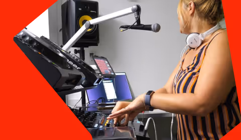 Woman DJ in striped dress adjusting audio mixer controls with microphone and headphones nearby.