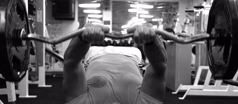 A man lifting weights on his back in a gym.