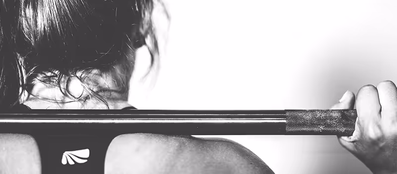 A woman lifting a bar weight whilst working out.