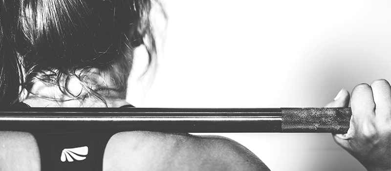 A woman lifting a bar weight whilst working out.