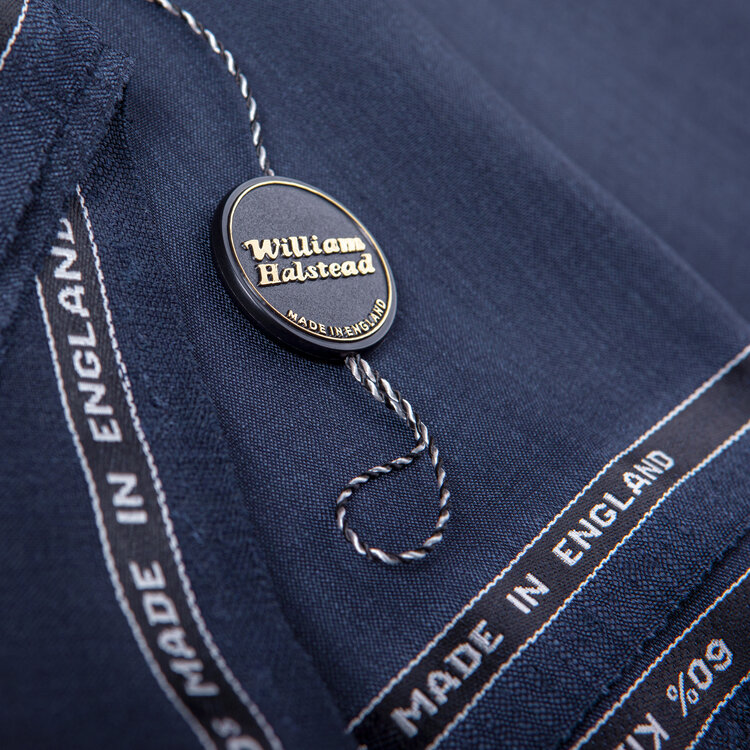 Product shot of a makers tag on fine folded woven textile that reads Made in England. 