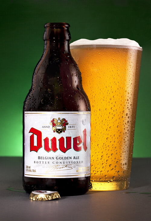 A product shot of a bottle of lager next to a pint glass full of lager on a green background.