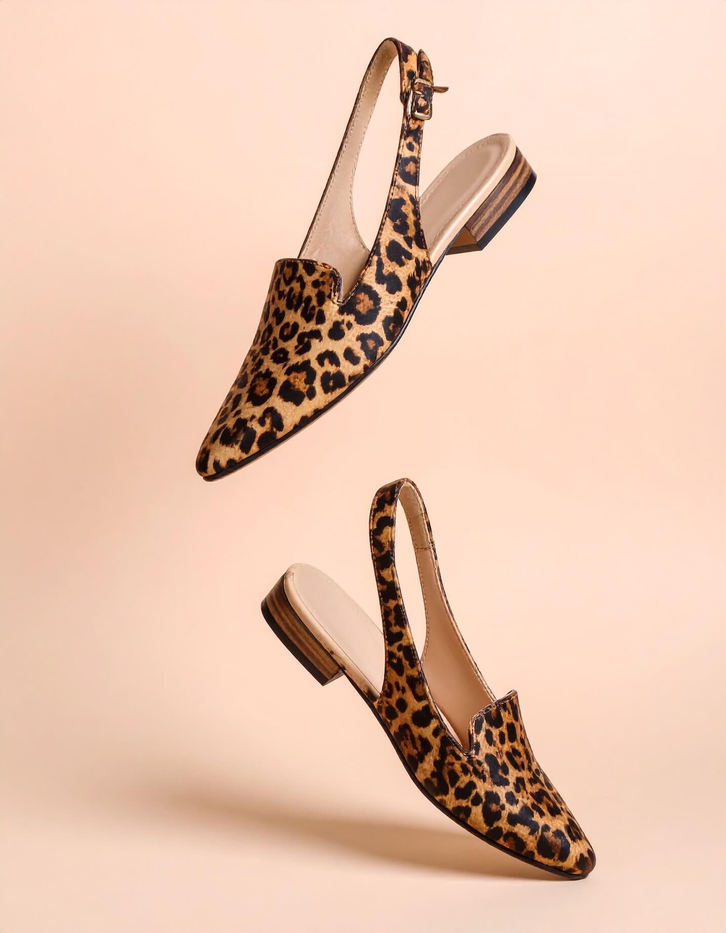 A product shot of some animal skin print ladies shoes suspended in air on a cream gradient backdrop.