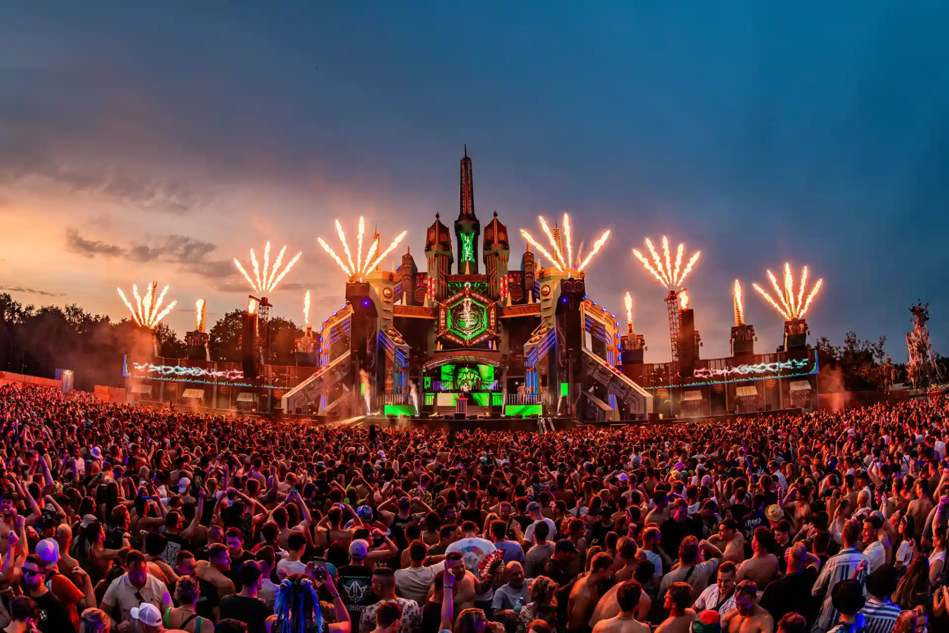 Decibel Outdoor festival stage with massive crowd and spectacular fireworks at sunset
