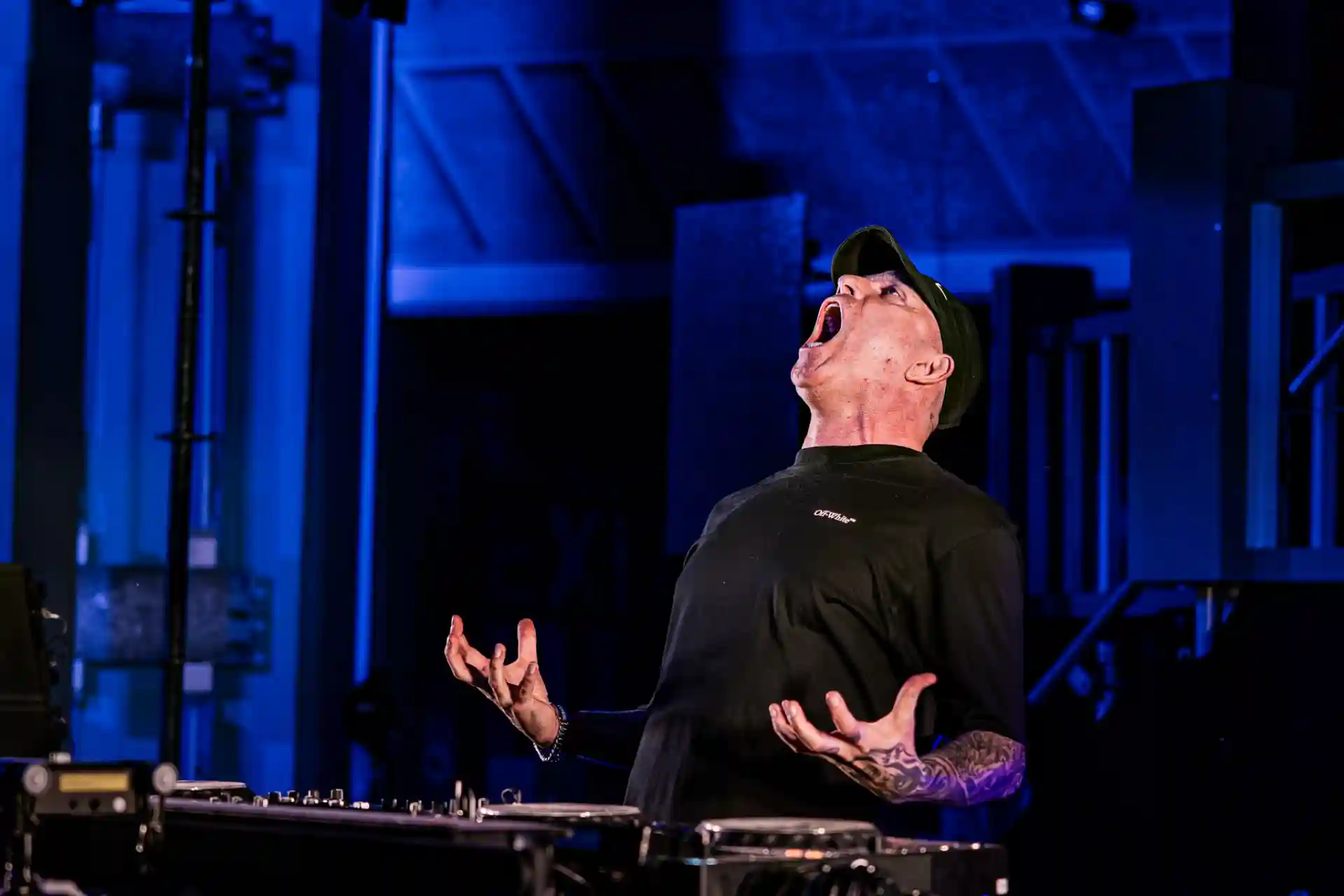 Decibel Outdoor DJ performing with intense energy on blue-lit stage
