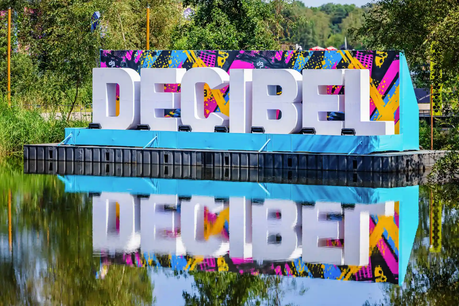 Decibel Outdoor festival sign with vibrant colors reflected in water