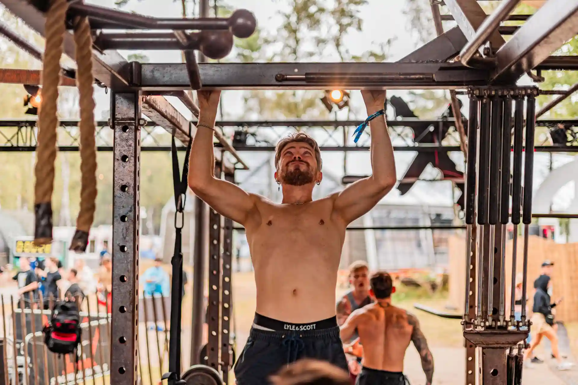Decibel Outdoor fitness event with athletes performing pull-ups on metal rig
