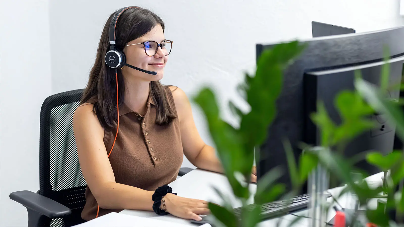 Mitarbeiterin mit Headset arbeitet am Computer im Büro