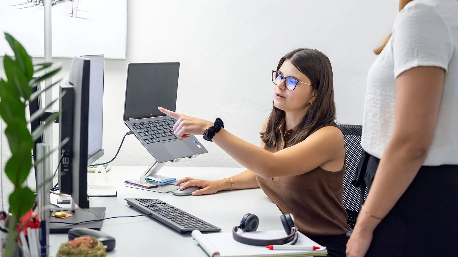 Mitarbeiterin der Gemeindeverwaltung zeigt am Computerbildschirm eine Aufgabe und erklärt diese einer Kollegin