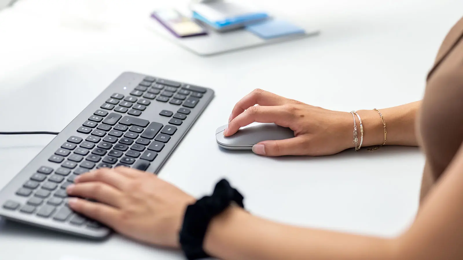 Nahaufnahme einer Mitarbeiterin der Gemeindeverwaltung bei der Arbeit mit Tastatur und Maus
