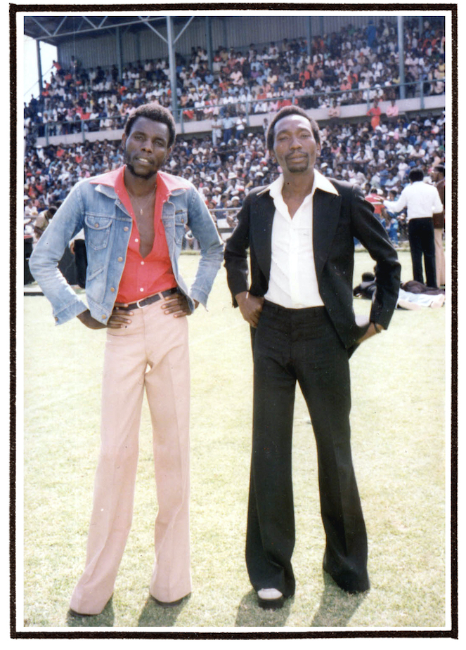 Oliver Mtukudzi and Thomas Mapfumo pose in a soccer stadium.