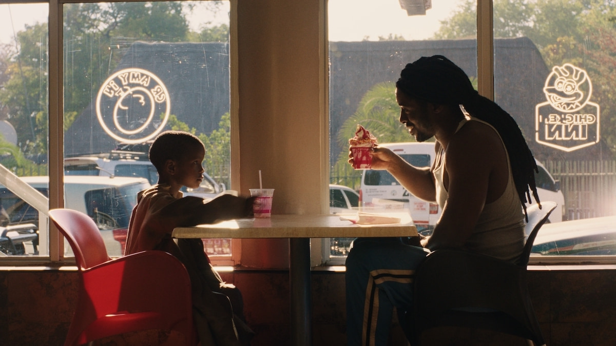 A young boy and his boxing coach eat desserts in a restaurant.