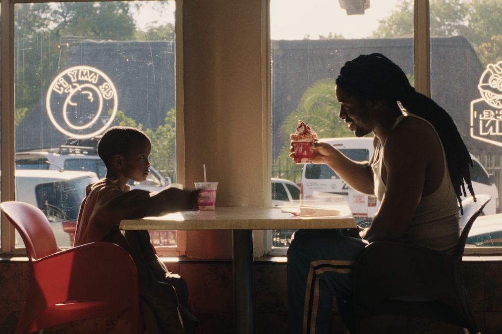 A young boy and his boxing coach eat desserts in a restaurant.