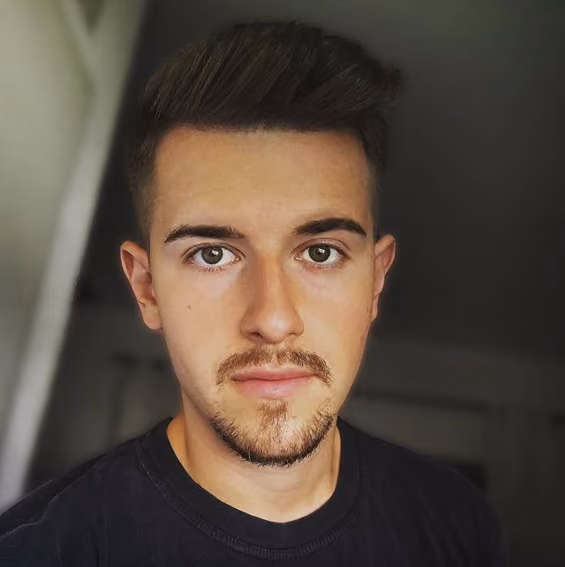 Porträt eines jungen Mannes mit kurzen braunen Haaren, braunen Augen und leichtem Bart.
