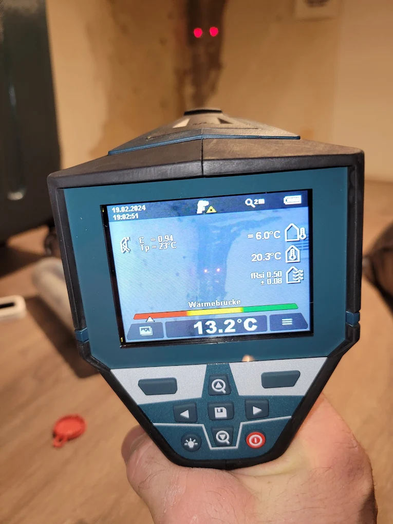 Messgerät Hydromette UNI 2 zeigt 25,8 mit zwei Sensoren an einem Holzboden und weißer Wand.