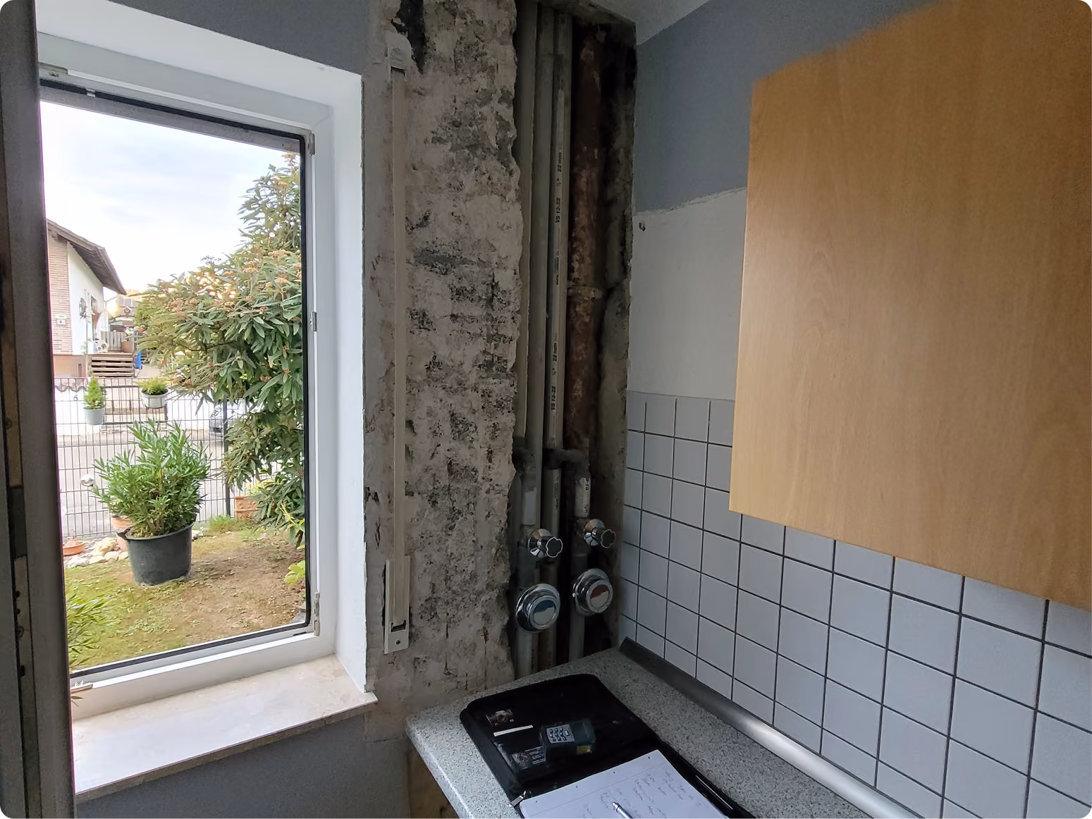 Decke eines Badezimmers mit sichtbarem Schimmelbefall und mit Plastikfolie abgedeckten Wänden und Fenster.