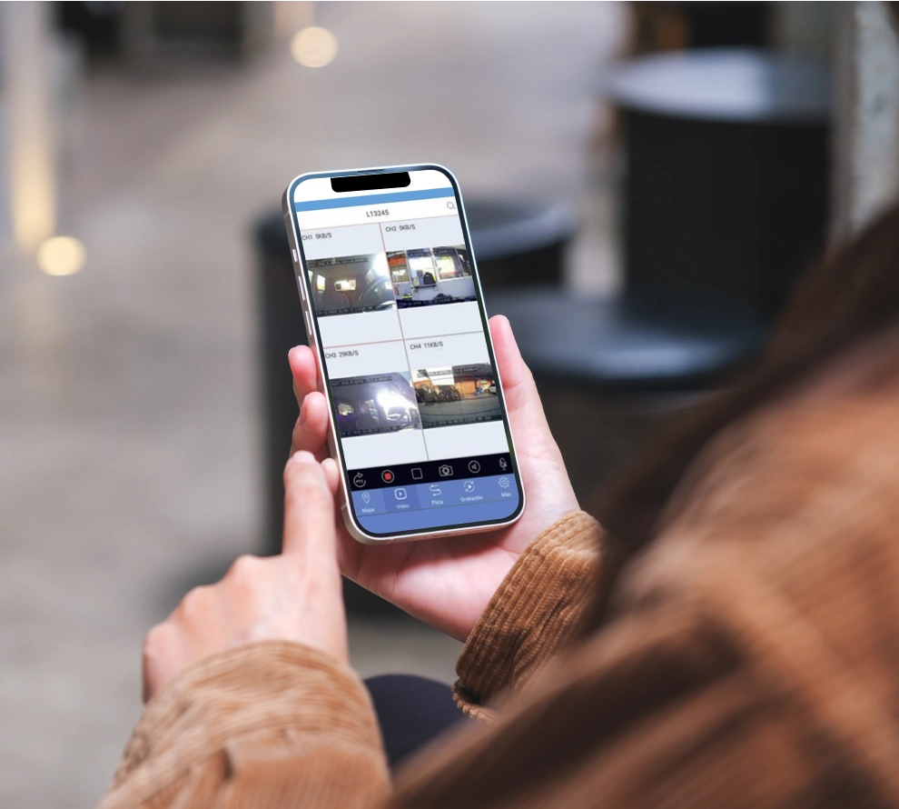 Person holding a smartphone displaying a security camera app with four live video feeds.