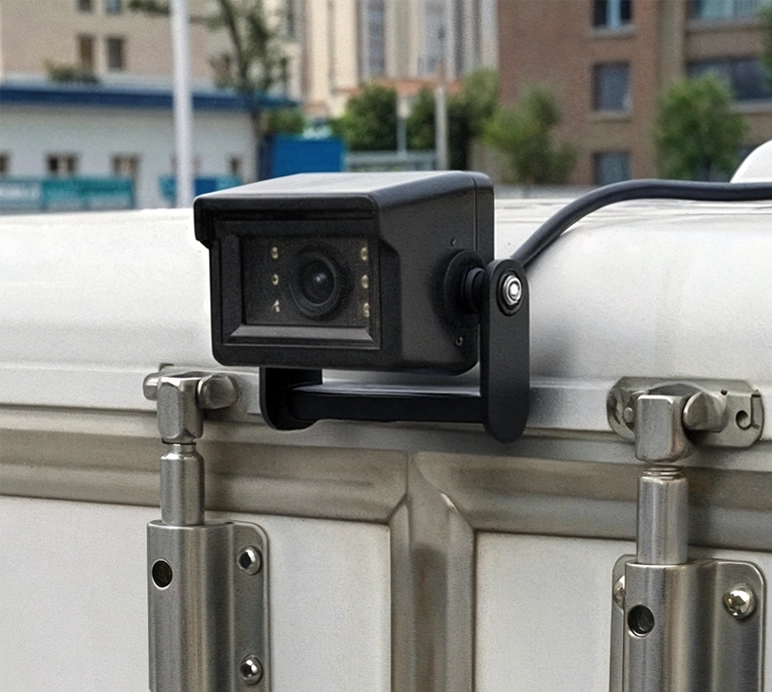 Close-up of a black security camera mounted on a white vehicle door with metal hinges.