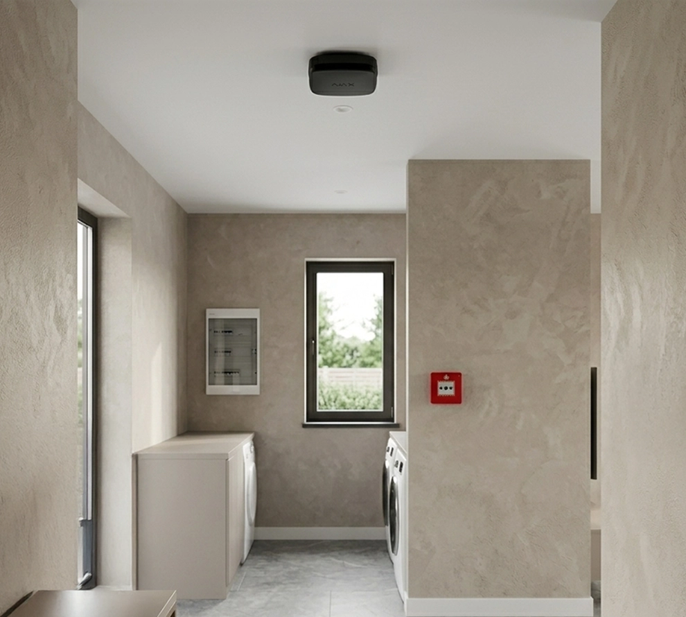 Minimalist laundry room with beige textured walls, a window, two front-loading washers or dryers, and a red fire alarm on one wall.