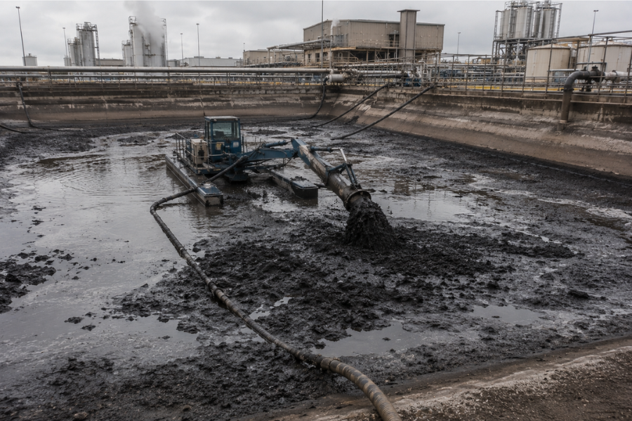 Mechanical dredging operation removing sludge from industrial wastewater lagoon