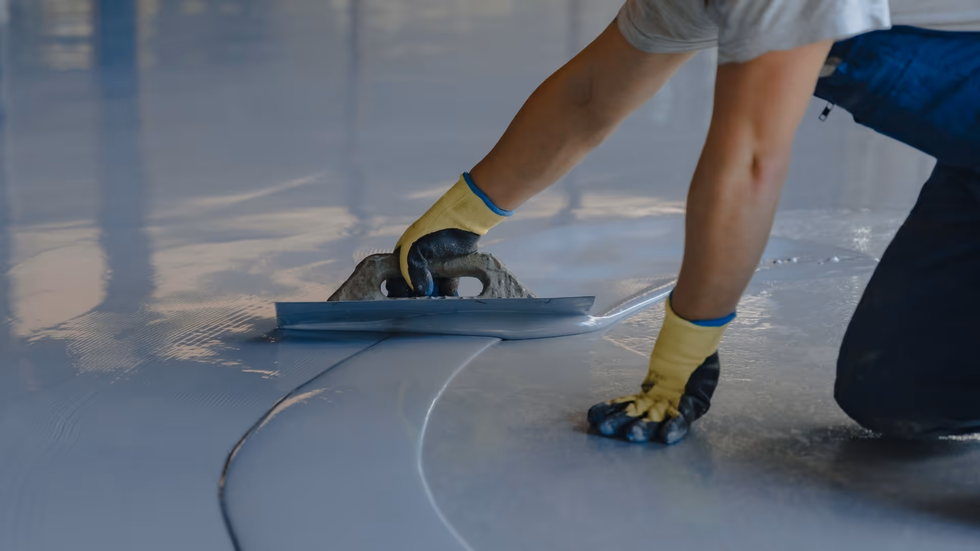 A floor coating expert smooths a layer of floor coating