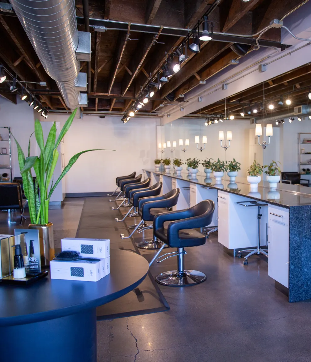 Modern loft-style interior of B. Young Salon featuring exposed brick walls, contemporary styling chairs, and natural lighting in Historic Old Town Wichita