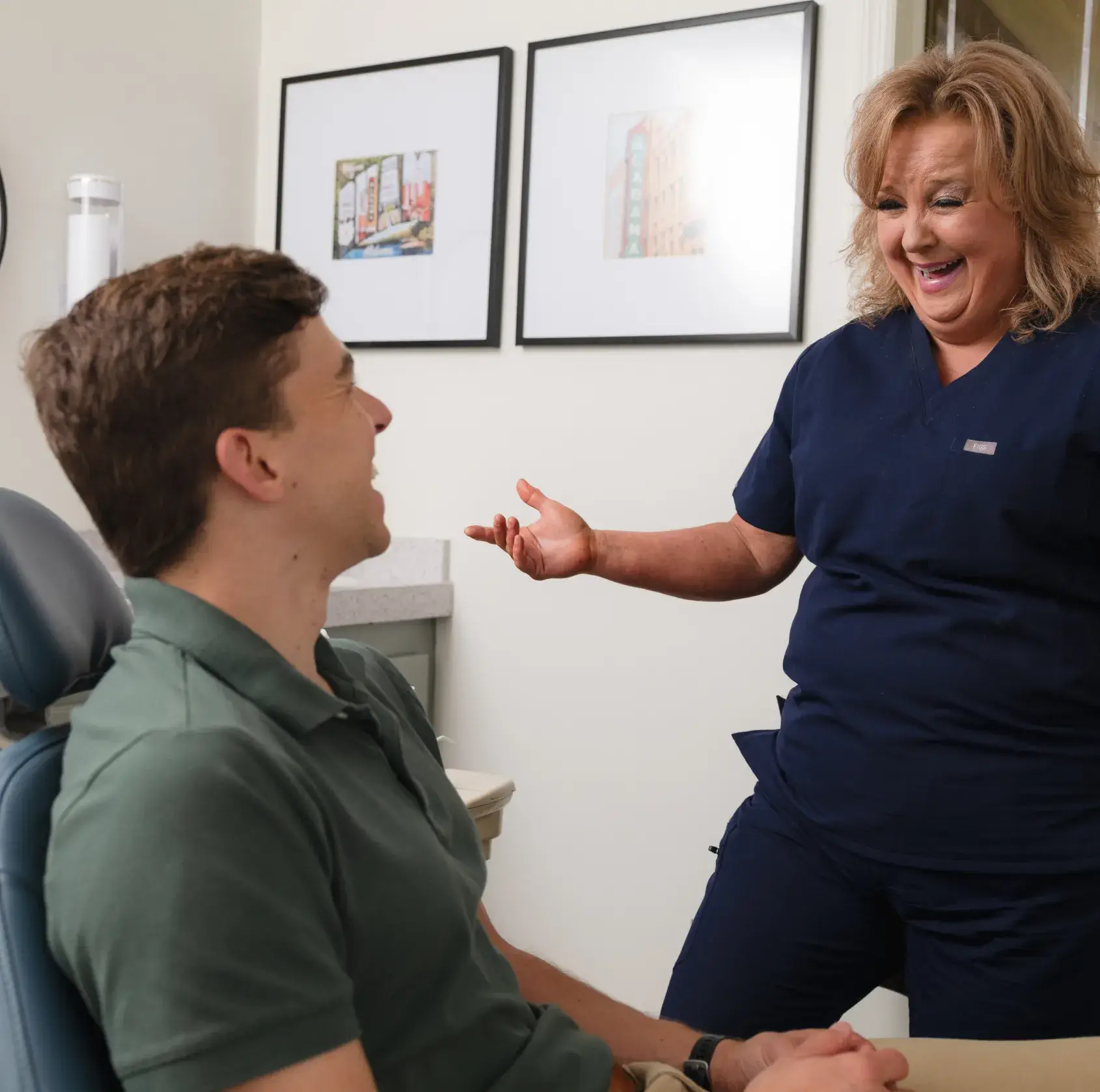 A woman talking to a man in a dentist chair.