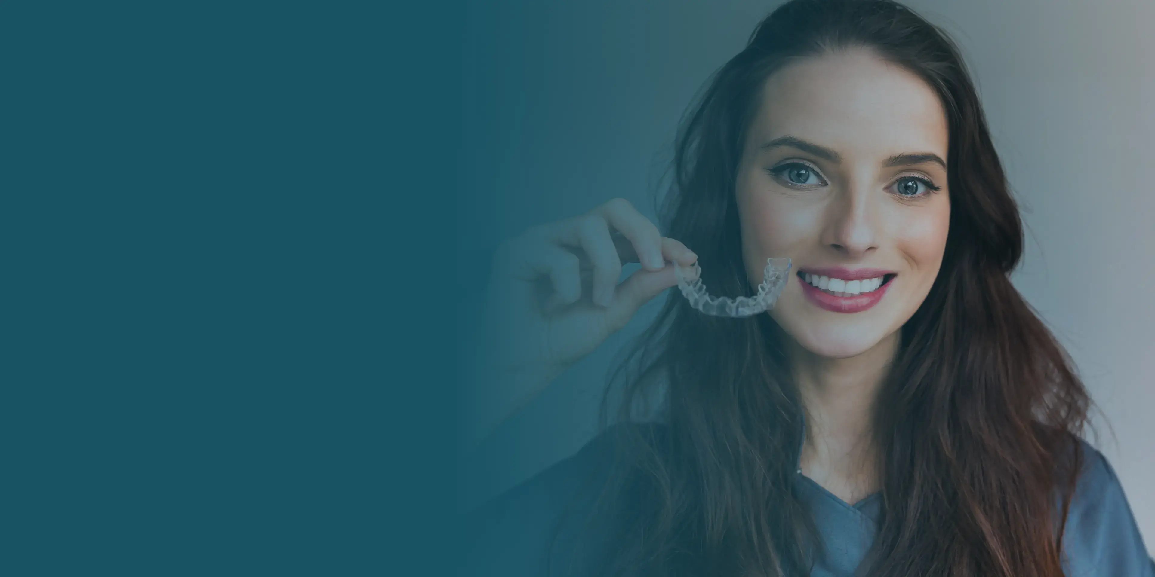 A woman holding a clearaligner to her teeth.