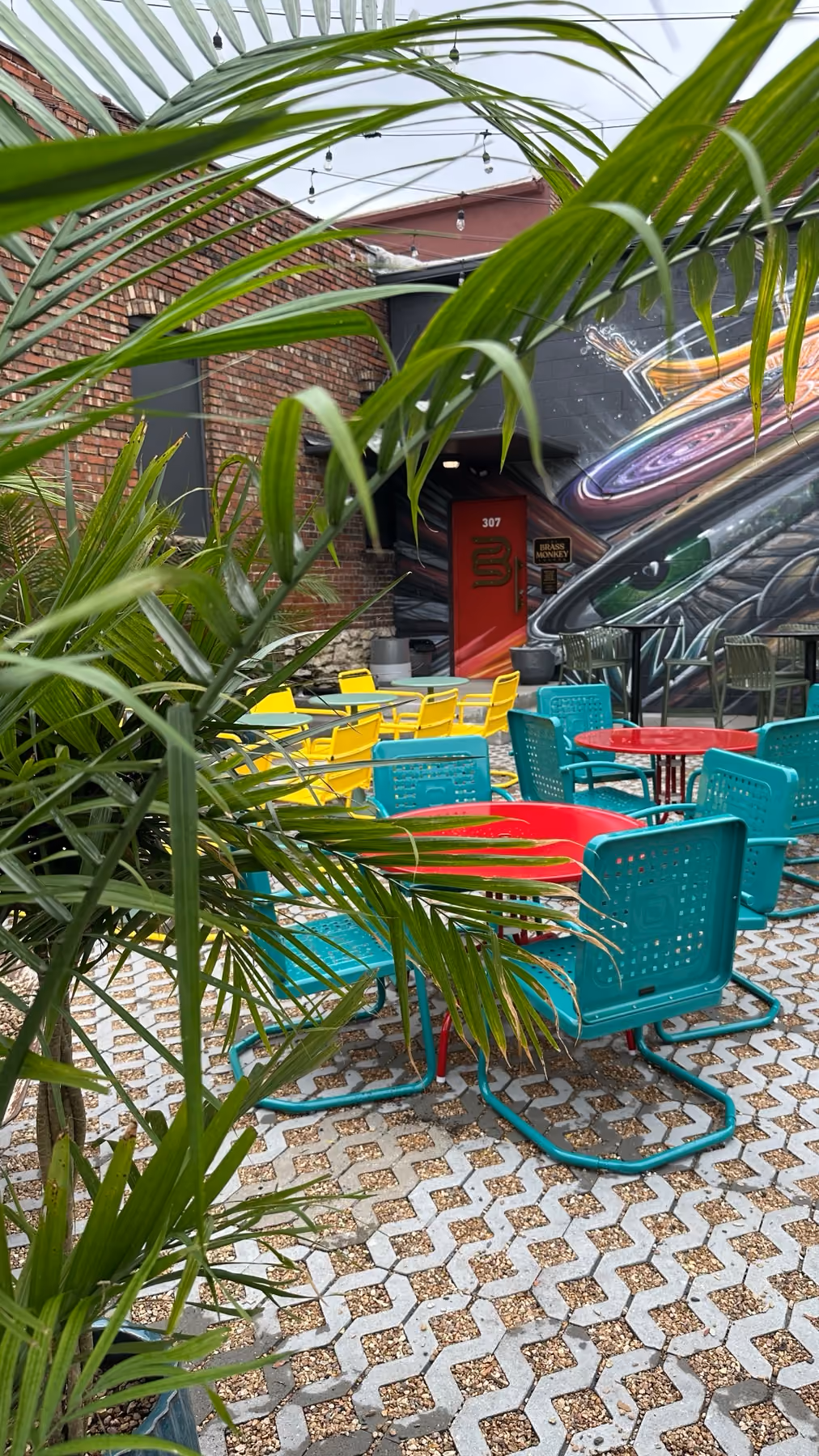 Colorful tables and accessible patio seating surrounded by tropical plants at Garden Bar.