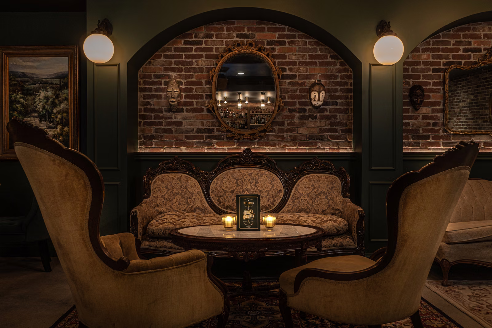 An intimate lounge seating arrangement with an ornate sofa, armchairs and candlelit table at Brass Monkey Lounge.