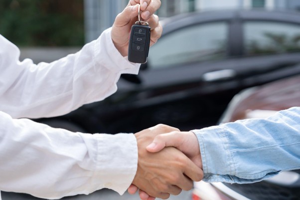 Dealer and private seller shaking hands while exchanging car keys during an off-the-street vehicle purchase