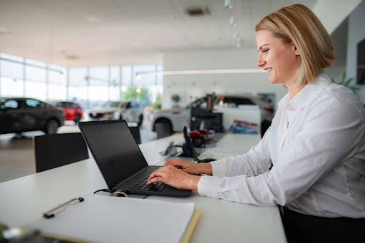 Dealership acquisition manager using laptop to source private-party vehicle leads