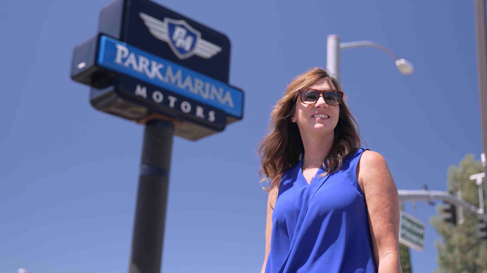 Brenna Stansberry standing beneath the Park Marina Motors sign