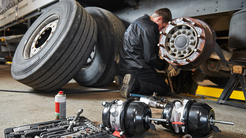 Truck repair service. Mechanic works with brakes in truck workshop