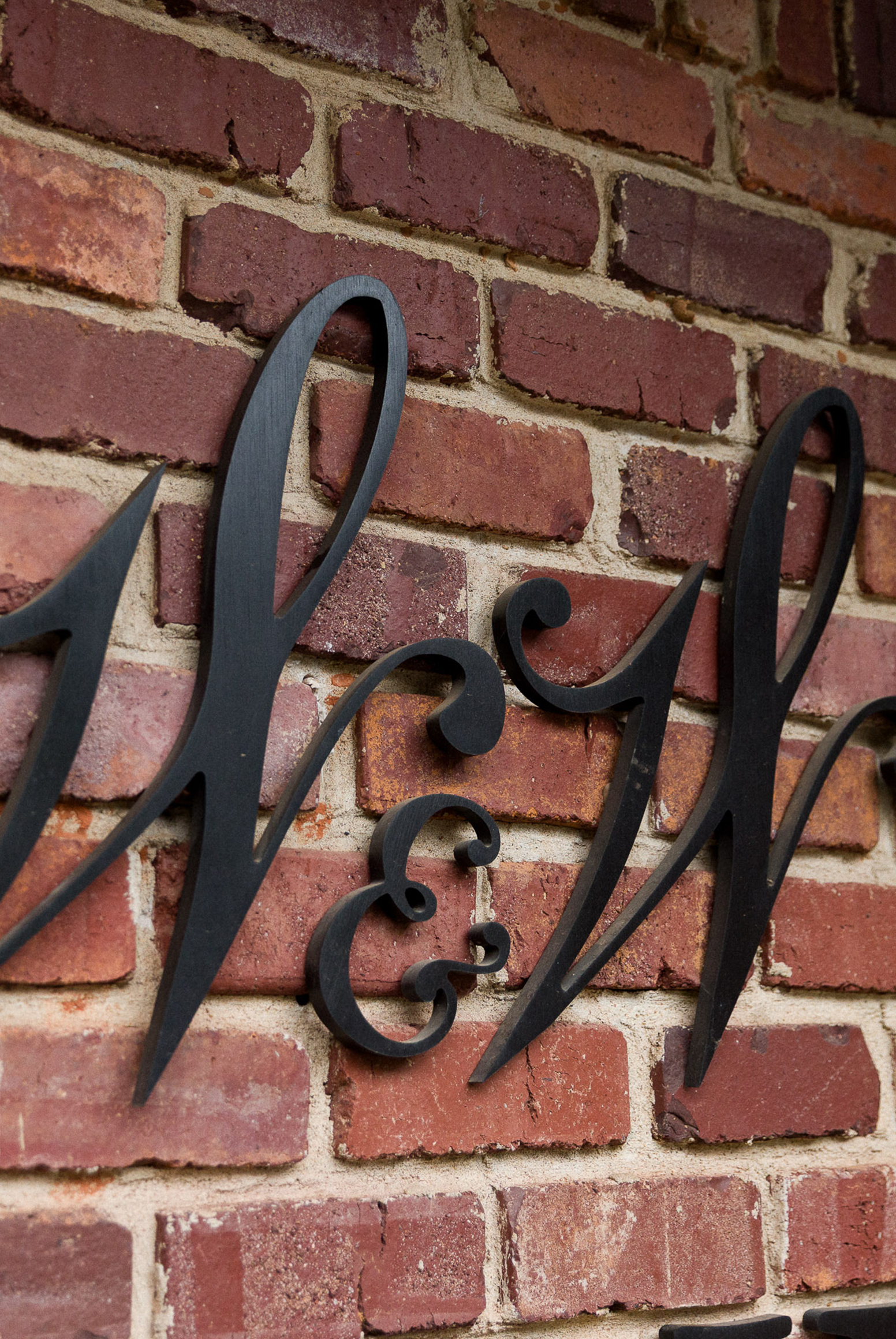 Black decorative metal letters W & W mounted on a red brick wall.