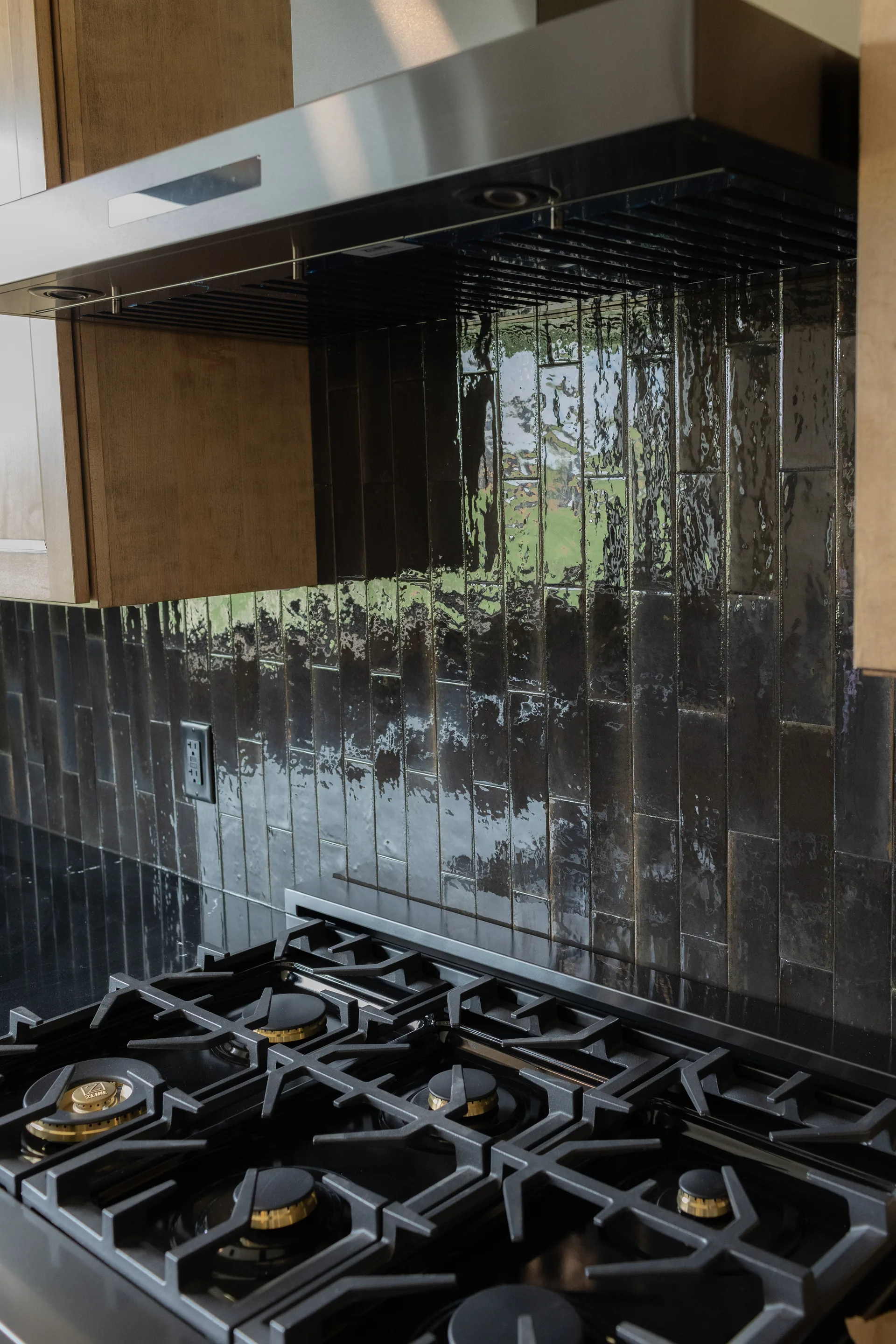 Gas range with black vertical-tile backsplash and custom wood hood
