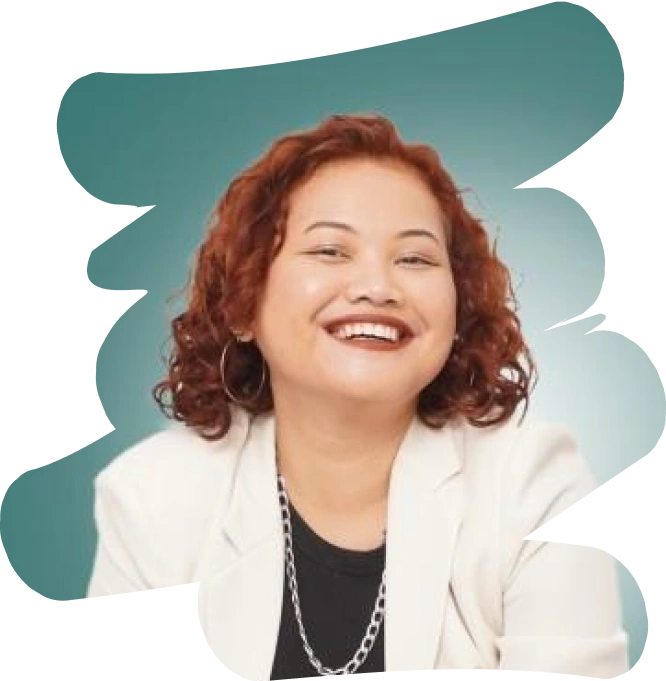 Smiling young woman with curly red hair, wearing a white blazer and black top with a silver chain necklace against a teal background.