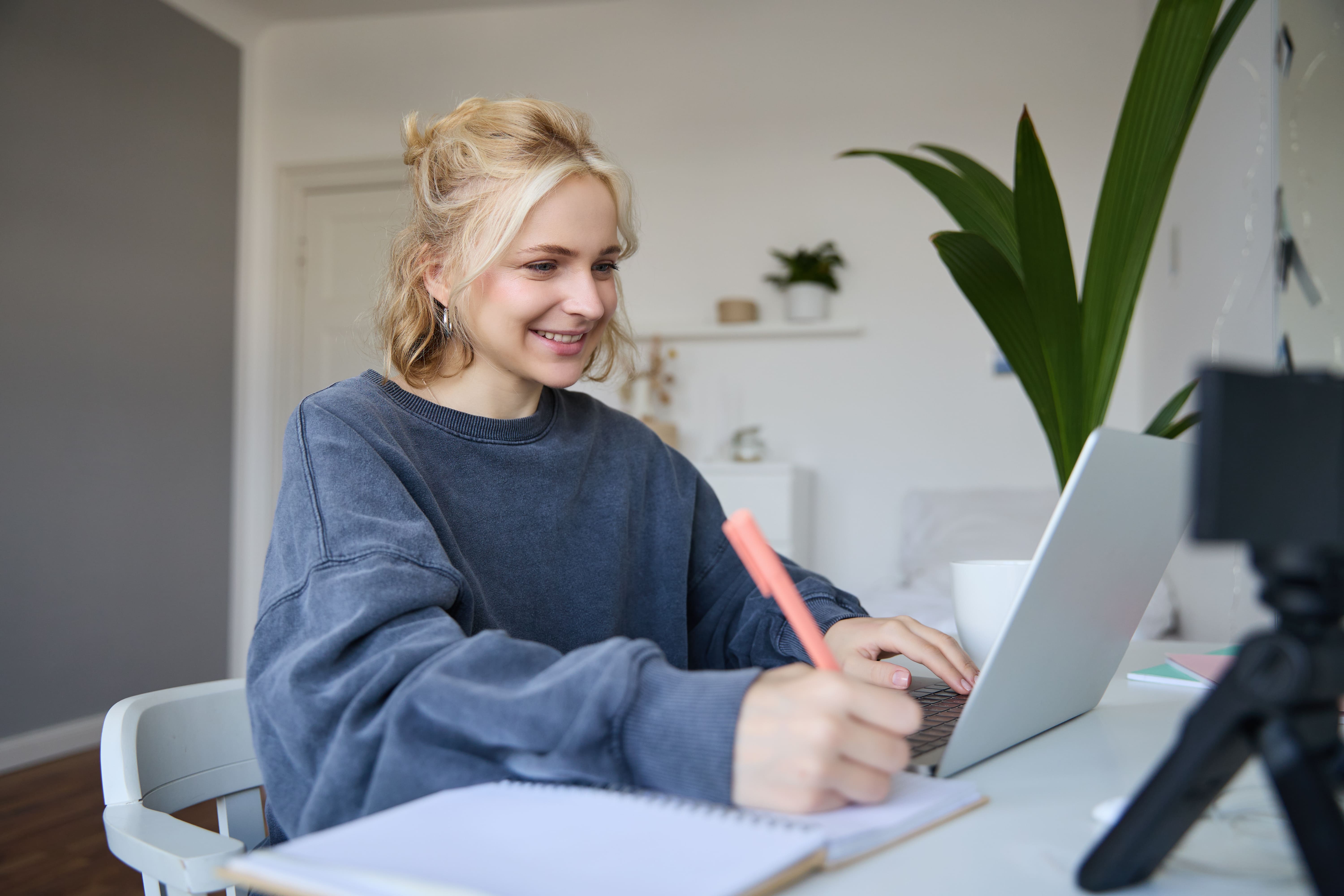 Student looking at laptop and writing on paper doing homework