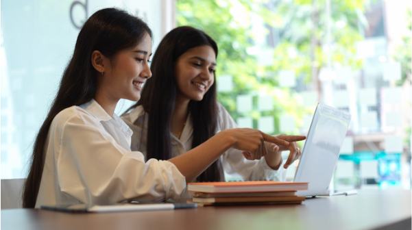 Two students sitting on a table looking at their laptop