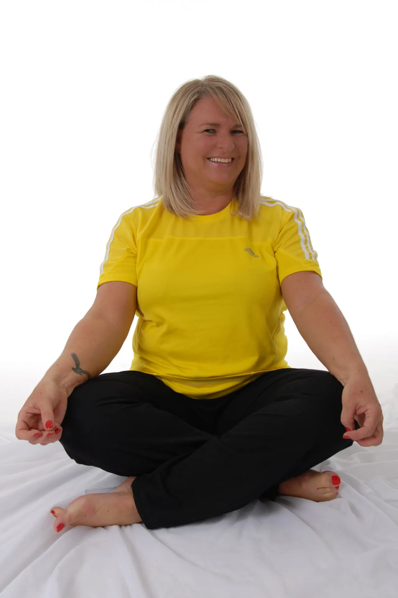 Sabine Jechow sitzt lächelnd im Schneidersitz mit Mudra-Gesten und strahlt innere Ruhe aus – ein authentisches Sinnbild für ihre Arbeit in den Bereichen Achtsamkeitstraining, Mentaltraining und Mindset Coaching.