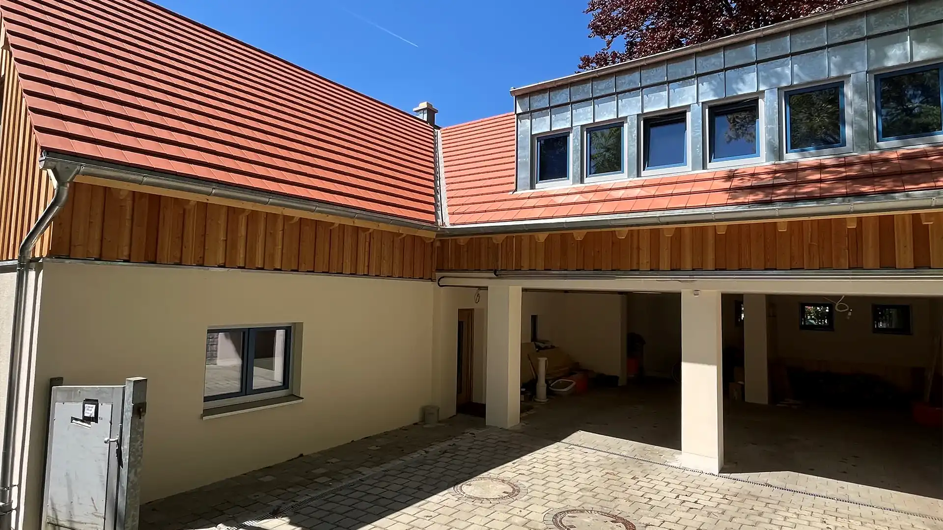 Neu renoviertes Wohnhaus mit frischem Anstrich, roten Ziegeldächern und modernen Fenstern. Die Garage ist offen und sauber, die Fassade ist hell und gepflegt.