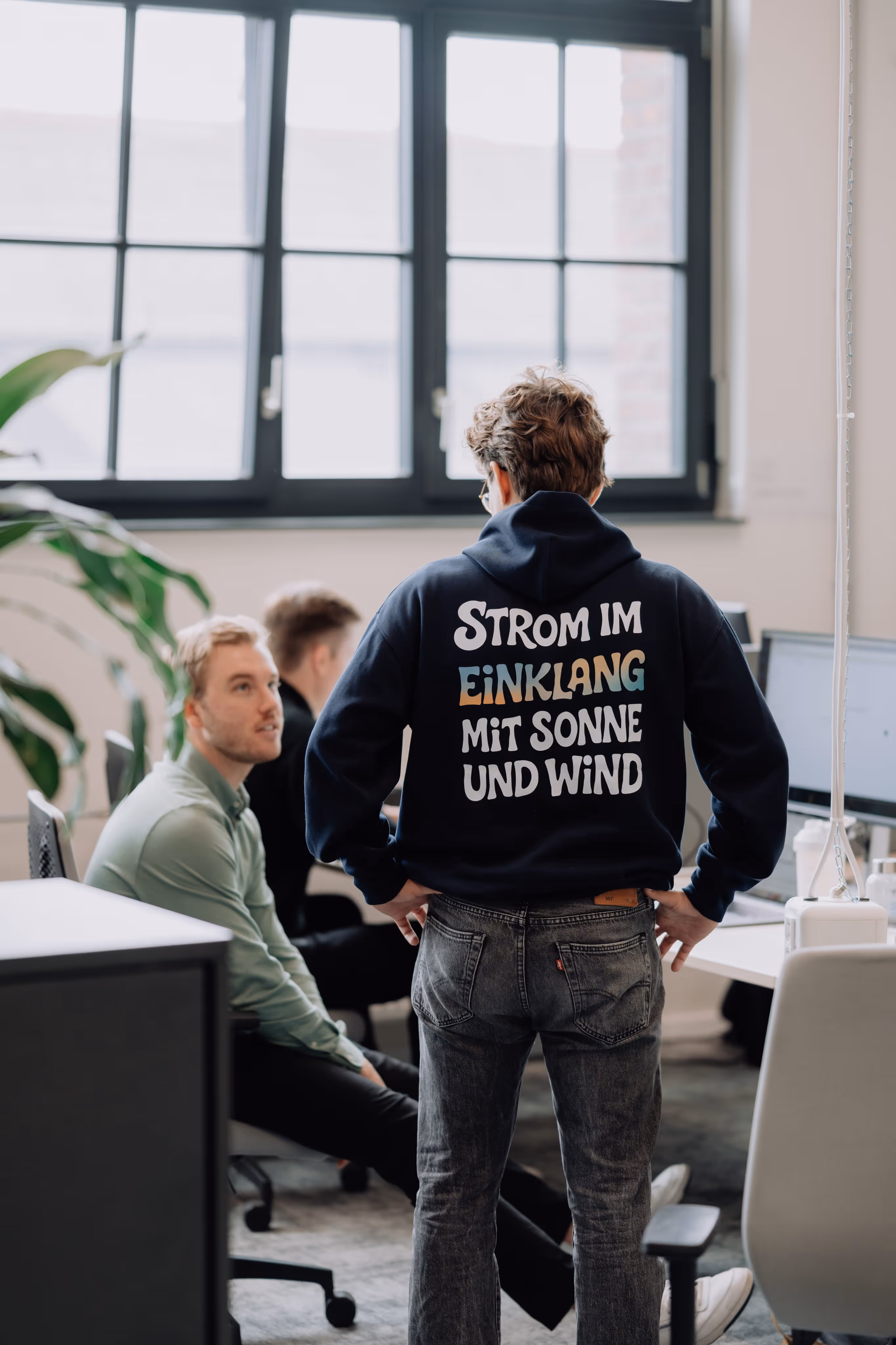 Einklang Mitarbeiter von hinten mit Pullover und der Aufschrift „Strom im Einklang mit Sonne und Wind“.