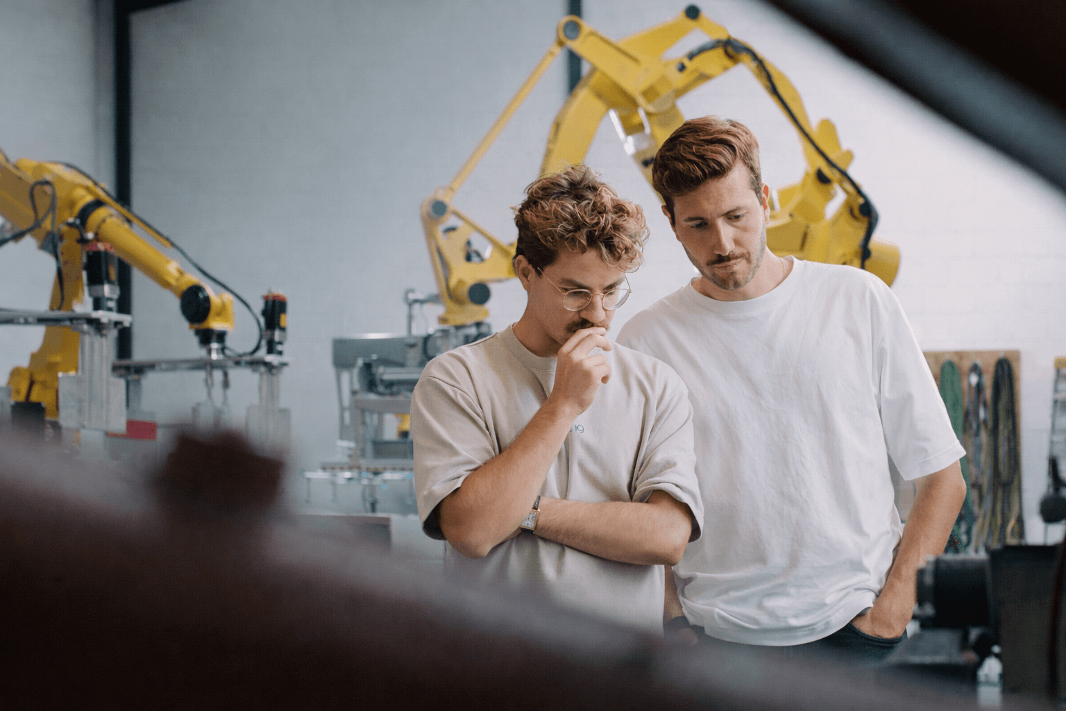 Zwei Männer stehen in einer Industriehalle und unterhalten sich vor Produktionsanlagen.