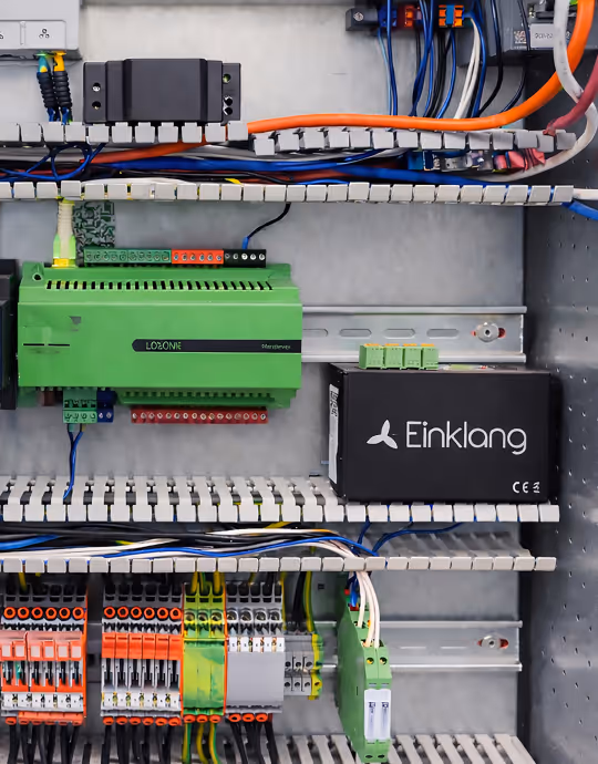 Elektronischer Schaltschrank mit grünen und schwarzen Logikmodulen und vielen Kabeln.