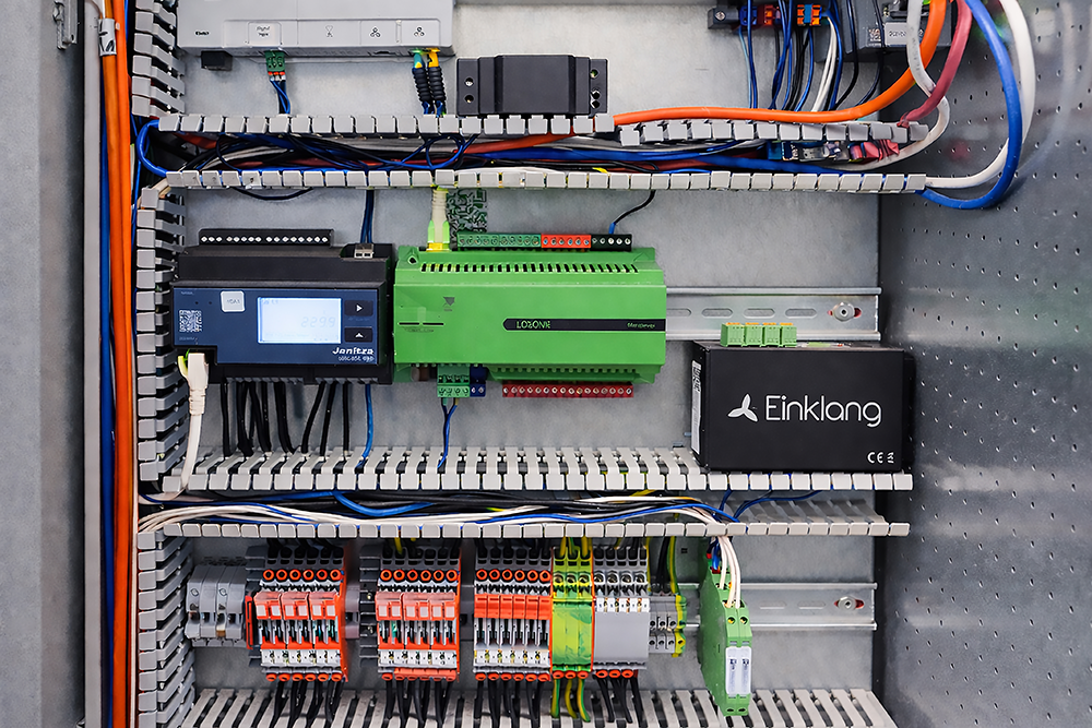 Elektronischer Schaltschrank mit grünen und schwarzen Logikmodulen und vielen Kabeln.
