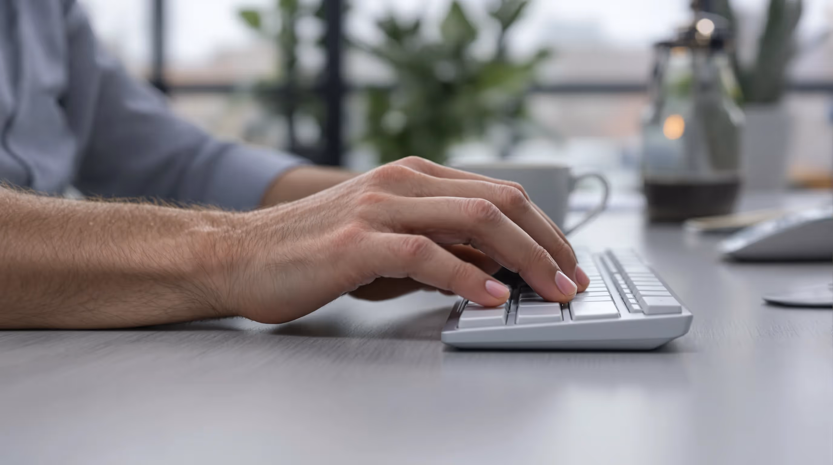 Worker rubs outer elbow while mousing with wrist extended at a UK desk.