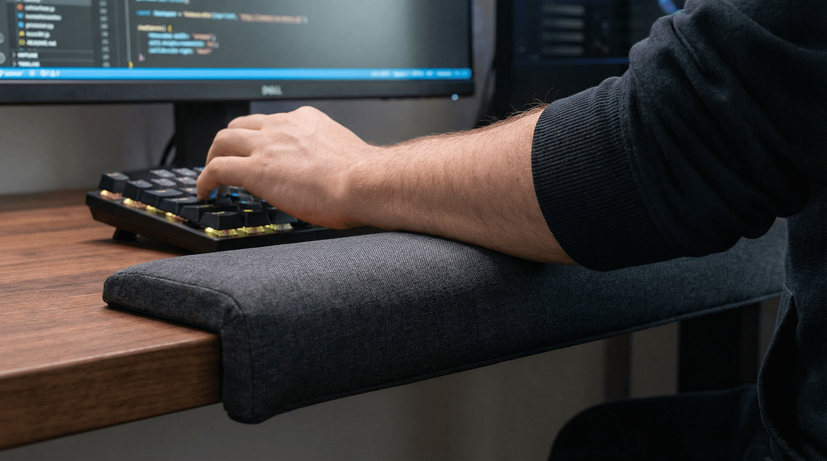 Forearm resting on long desk-edge pad for ergonomic elbow support.