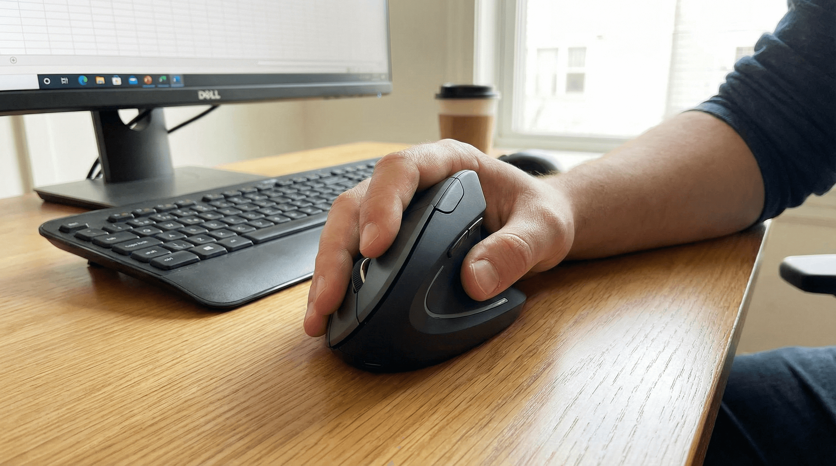 Hand using an adjustable ergonomic mouse with palm support at a desk.